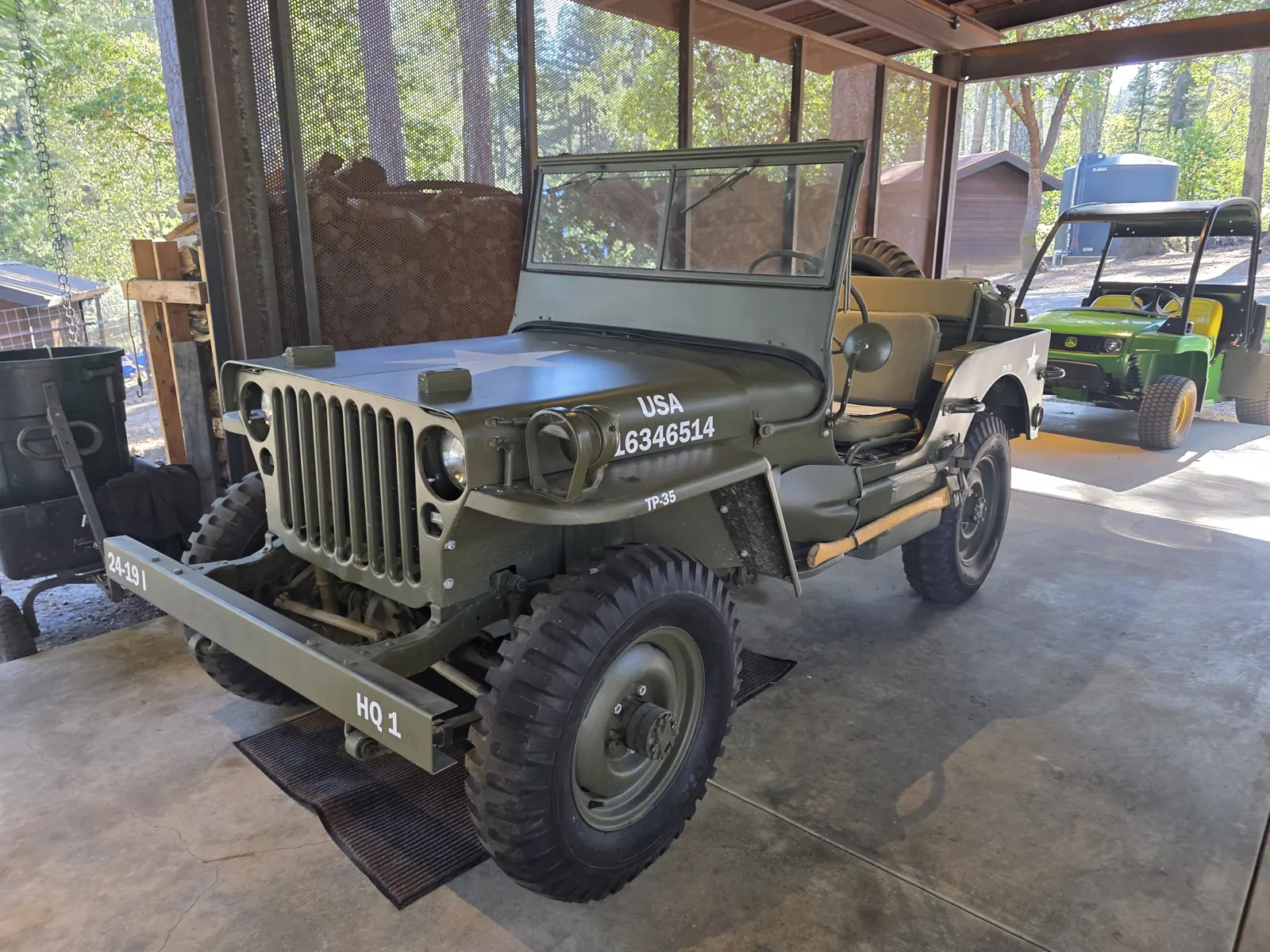 Olive drab 1944 Willys MB Jeep with white star and hood number, parked in an open-sided barn during a classic vehicle VIN verification.