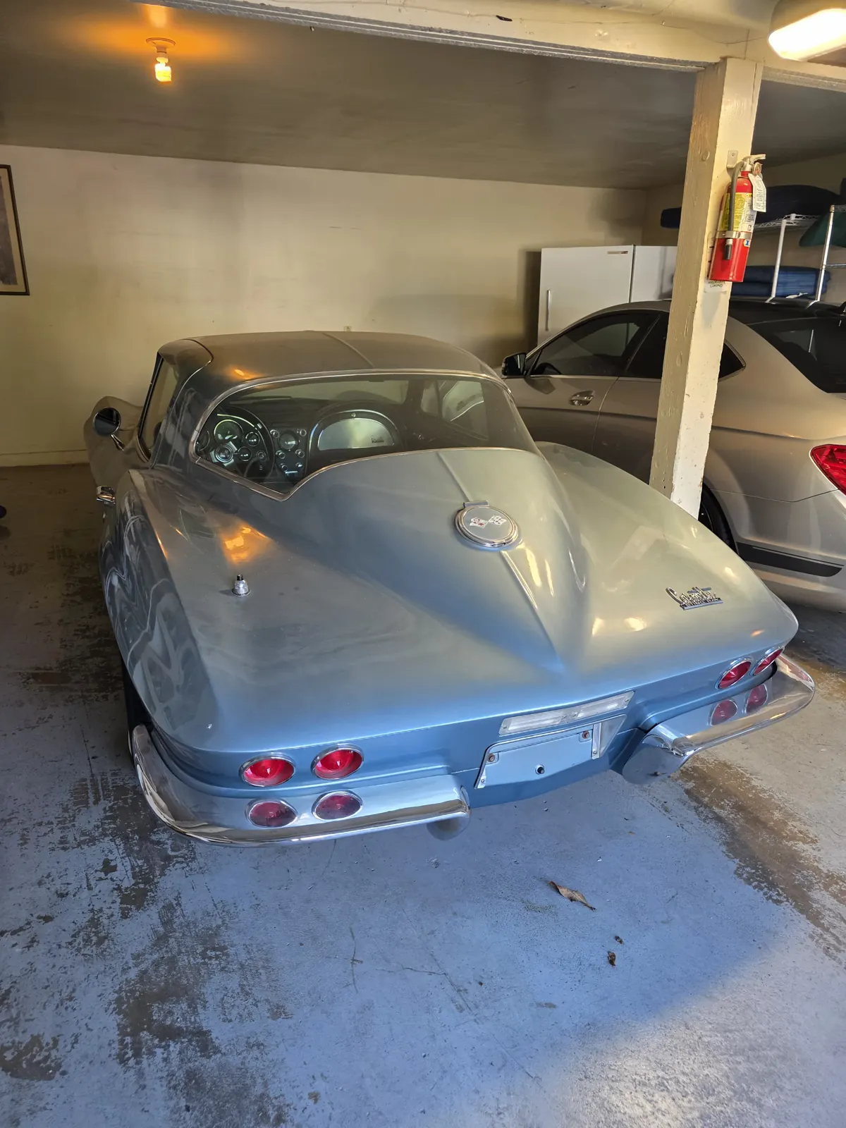 Light blue 1960s Chevrolet Corvette Sting Ray coupe parked in a home garage during a classic car VIN verification.