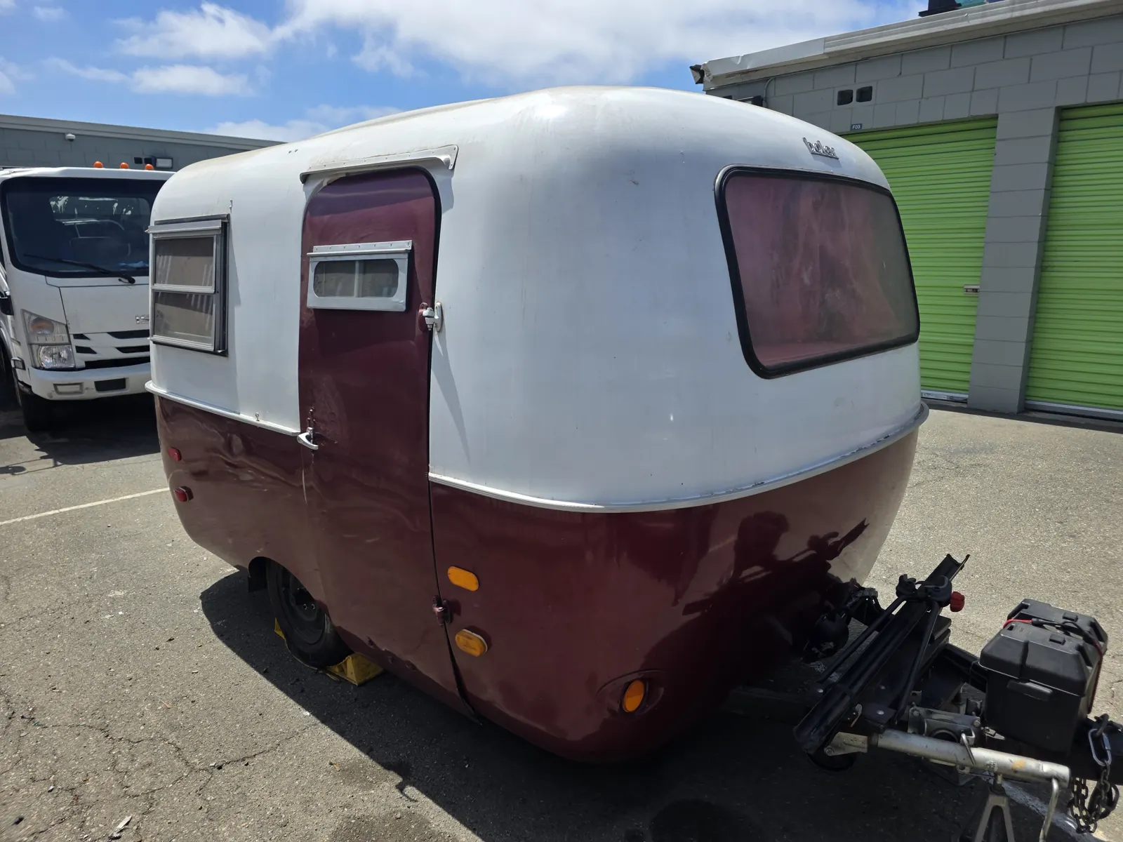 Vintage white and maroon Boler fiberglass travel trailer parked in a lot during a trailer VIN verification.