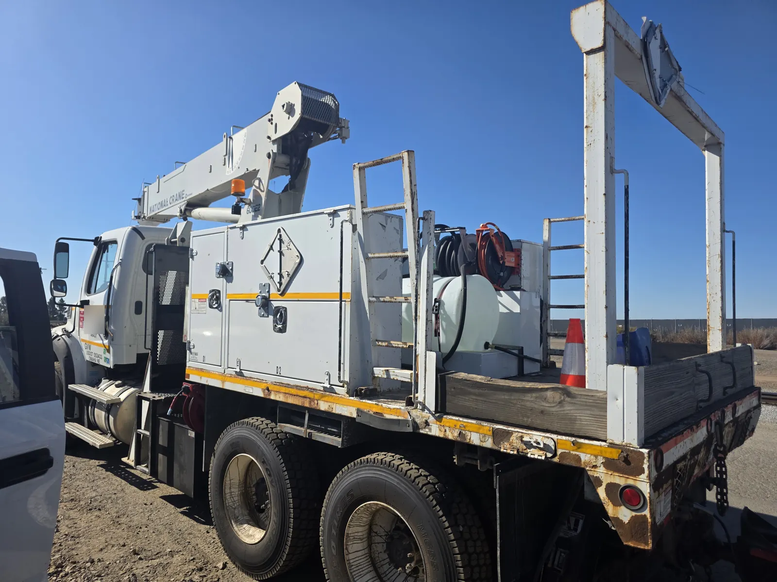 Rear three-quarter view of a crane service truck with tool cabinets and a flatbed deck, photographed during a VIN verification.