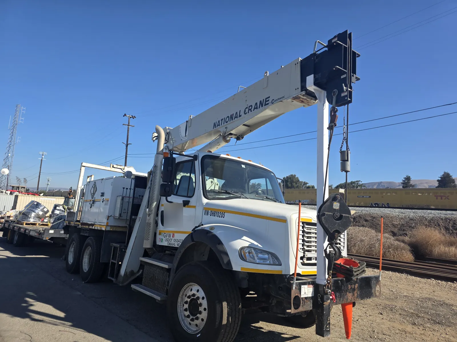 Freightliner crane truck parked beside railroad tracks for an on-site commercial VIN verification.
