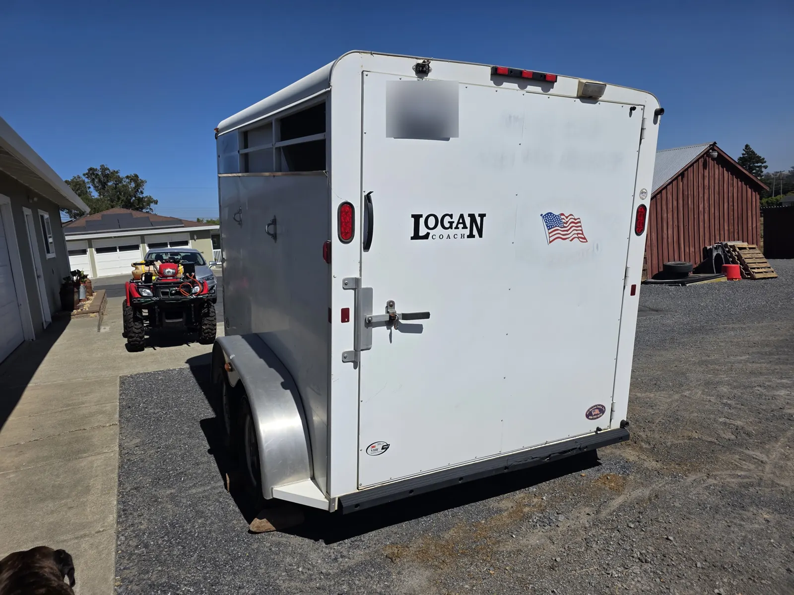 White Logan Coach two-horse trailer parked on gravel beside a barn during a mobile trailer VIN verification.