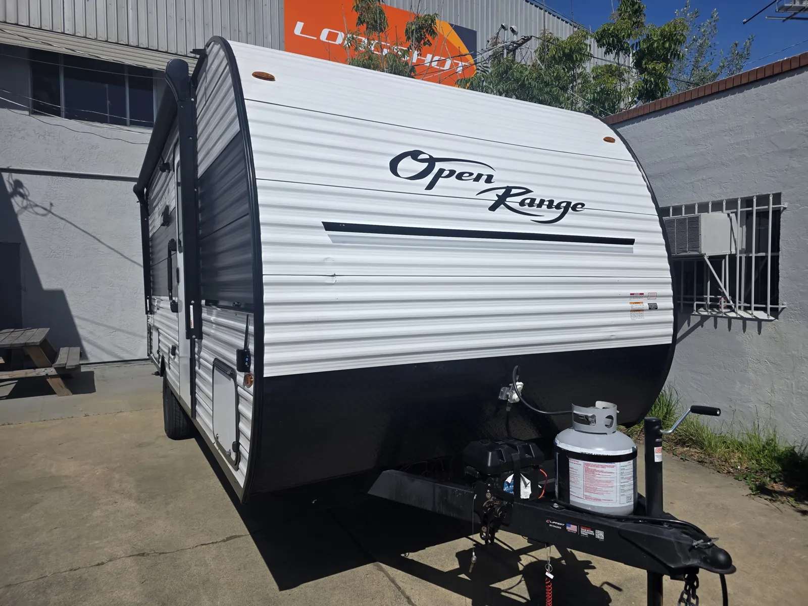 White Open Range Colt travel trailer with a propane tank on the tongue, parked outside the Innovo shop in Oakland for a VIN verification.