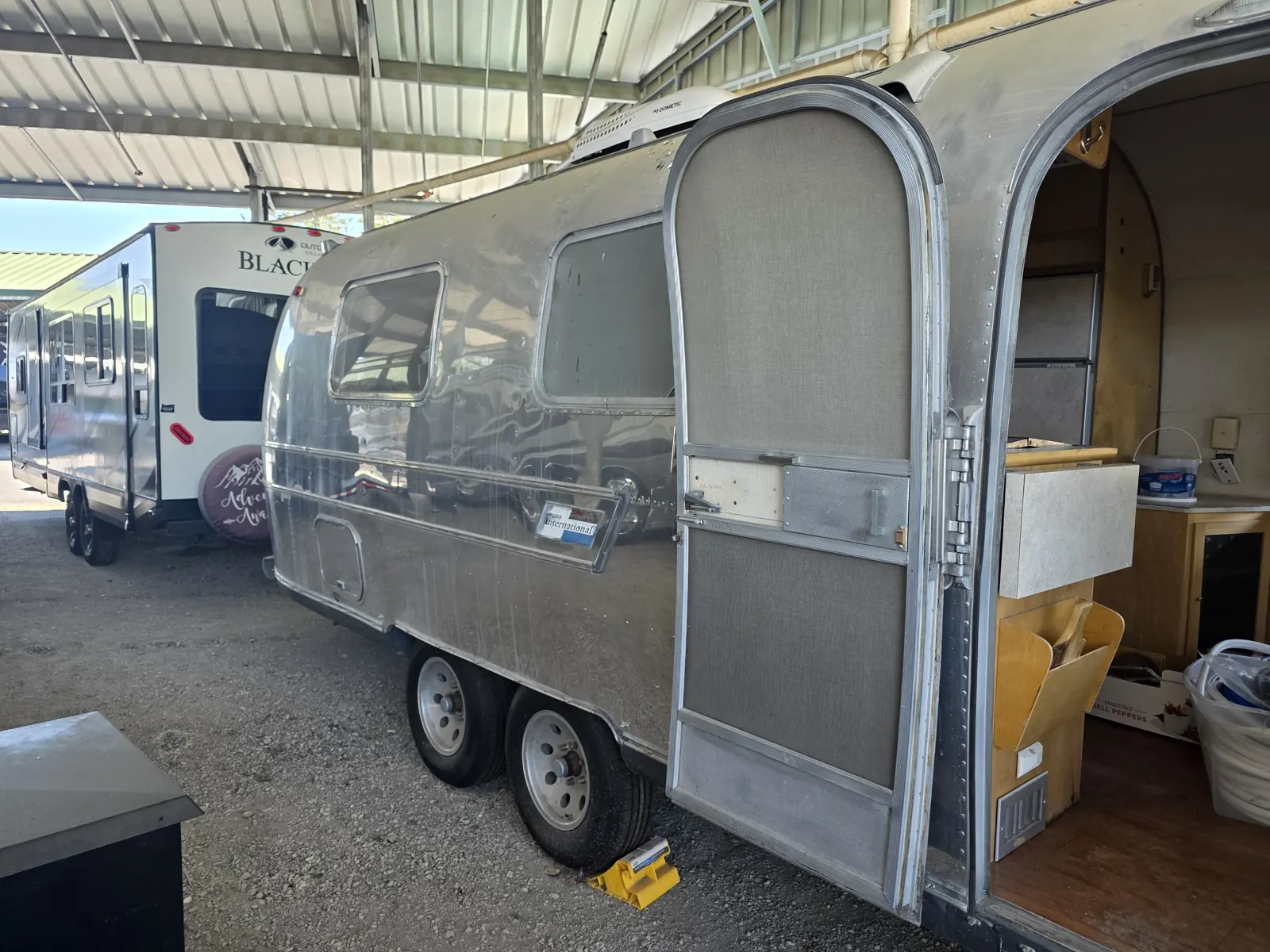 Polished vintage Airstream International travel trailer under a covered storage canopy during a VIN verification.